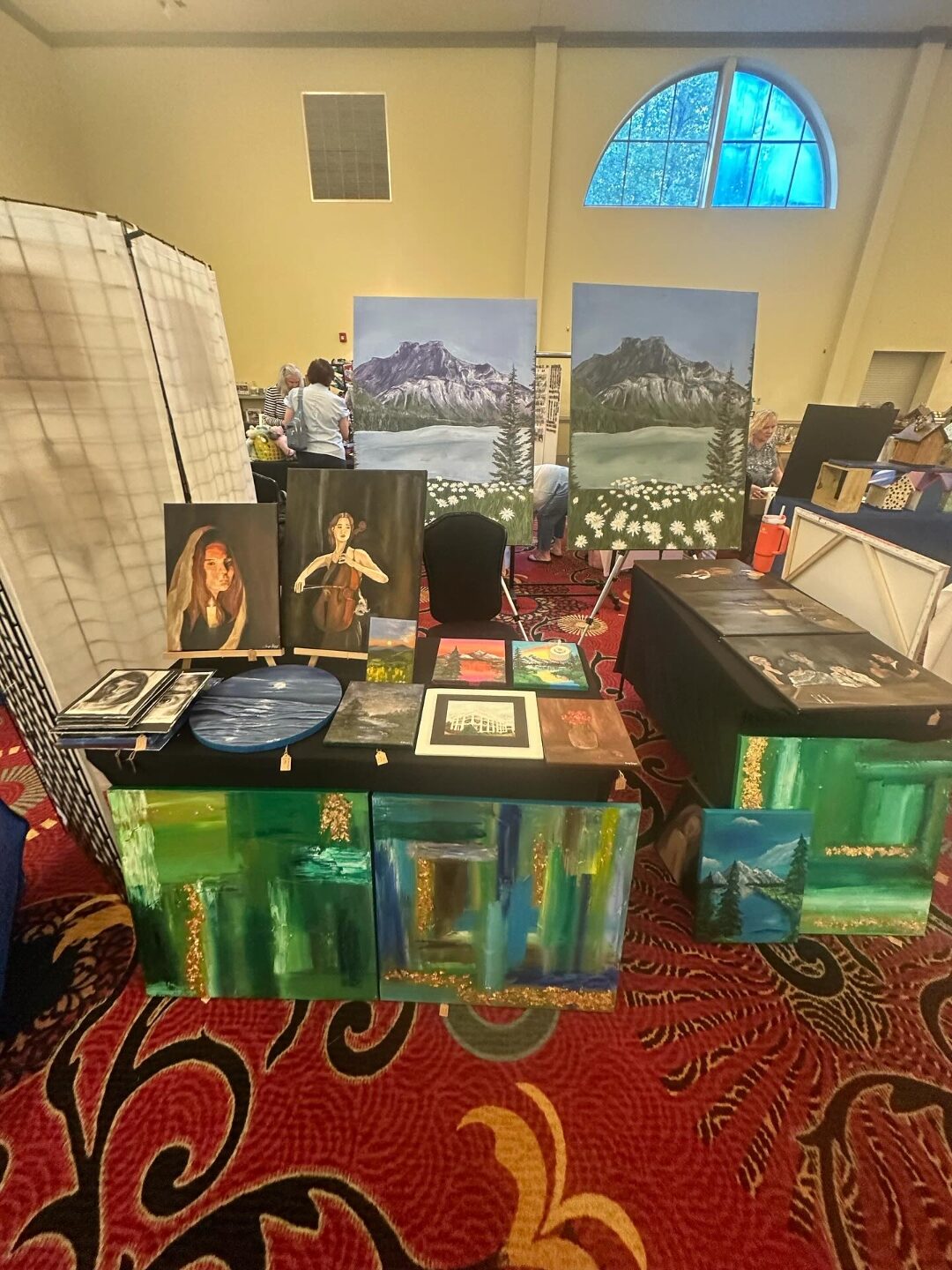 Indoor art market table display of Aniya's paintings