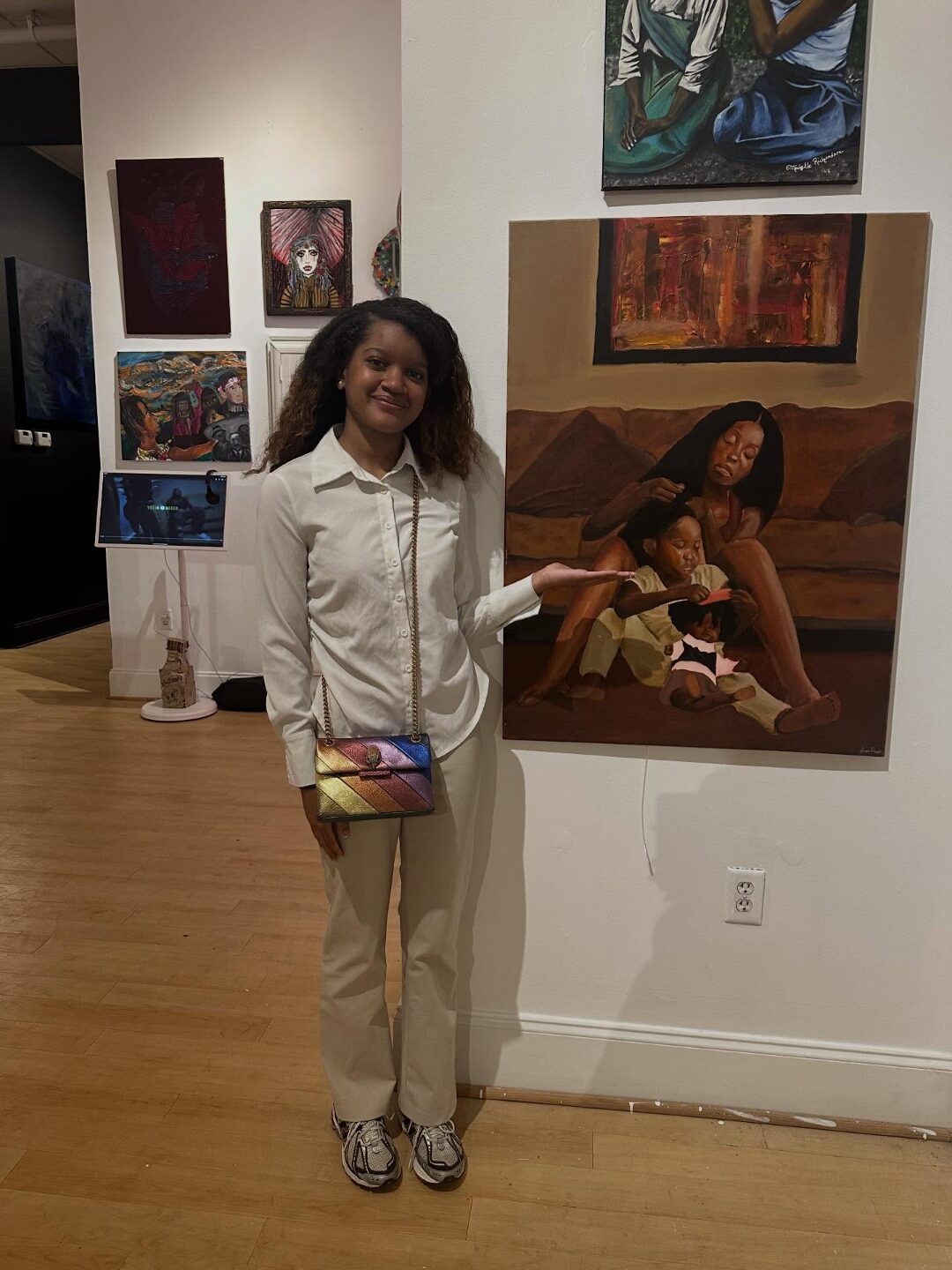 Aniya standing next to her painting Roots at a gallery exhibit