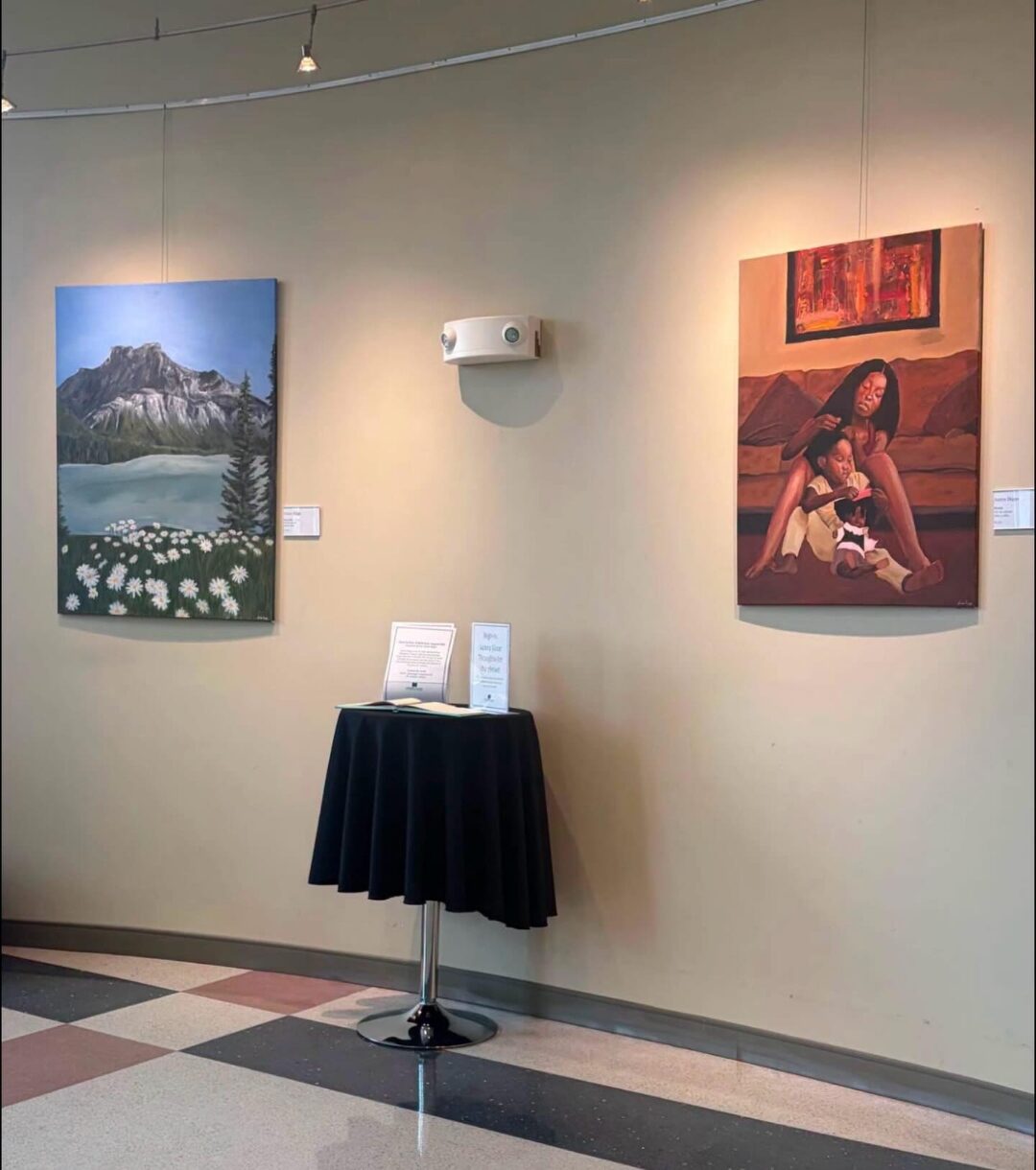 Two of Aniya's paintings hanging in a gallery lobby